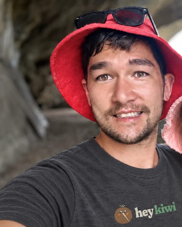 Joshua, the Kiwi behind Hey Kiwi, in a red sun hat and a Hey Kiwi t-shirt